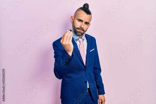 Young hispanic man wearing business suit and tie doing italian gesture with hand and fingers confident expression