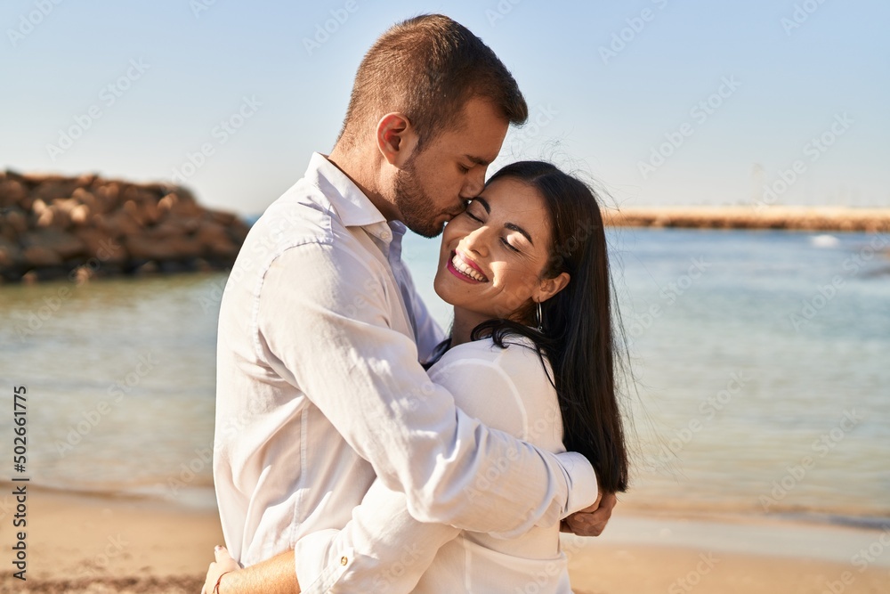 Man and woman couple smiling happy hugging each other standing at seaside Man and woman couple smiling happy hugging each other standing at seaside
