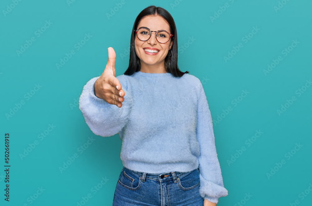 Young hispanic woman wearing casual clothes and glasses smiling friendly offering handshake as greeting and welcoming. successful business. Young hispanic woman wearing casual clothes and glasses smiling friendly offering handshake as greeting and welcoming. successful business.