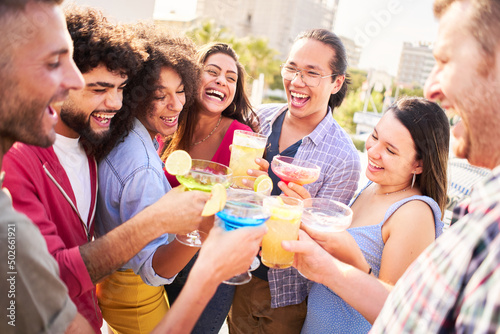 Group of happy friends drinking and toasting cocktails at brewery bar rooftop terrace restaurant. Friendship concept with young people having fun.