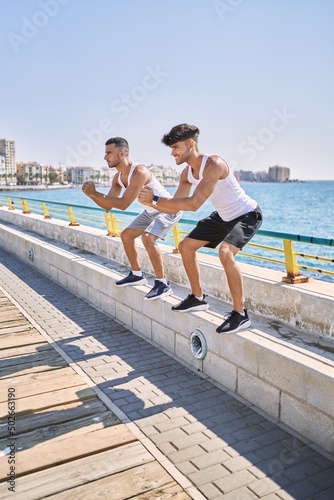 Two hispanic men couple smiling confident training at seaside