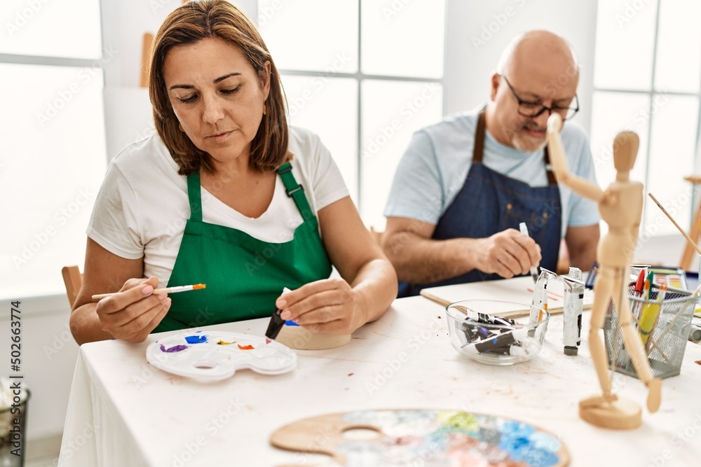 Middle age hispanic painter couple smiling happy painting at art studio. Middle age hispanic painter couple smiling happy painting at art studio.