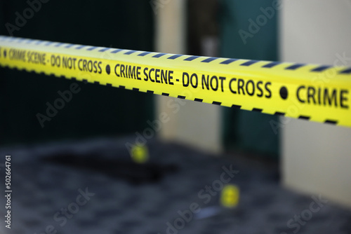 Crime scene tape for covering the area cordon. Yellow tape with blurred forensic law enforcement background in cinematic tone photo