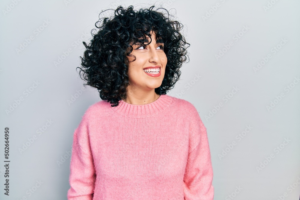 Young middle east woman wearing casual clothes looking away to side with smile on face, natural expression. laughing confident.
