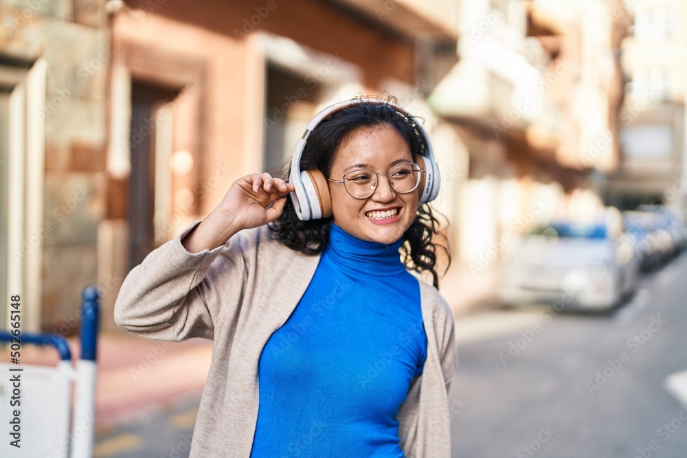 Young chinese woman smiling confident listening to music at street