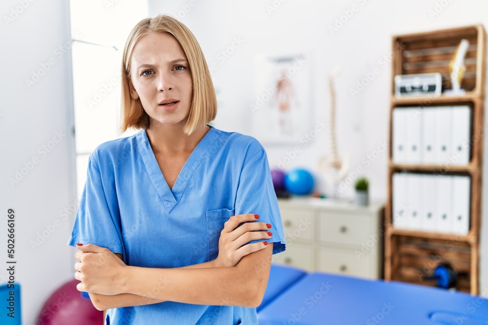 Young caucasian physiotherapist woman working at pain recovery clinic skeptic and nervous, disapproving expression on face with crossed arms. negative person. Young caucasian physiotherapist woman working at pain recovery clinic skeptic and nervous, disapproving expression on face with crossed arms. negative person.