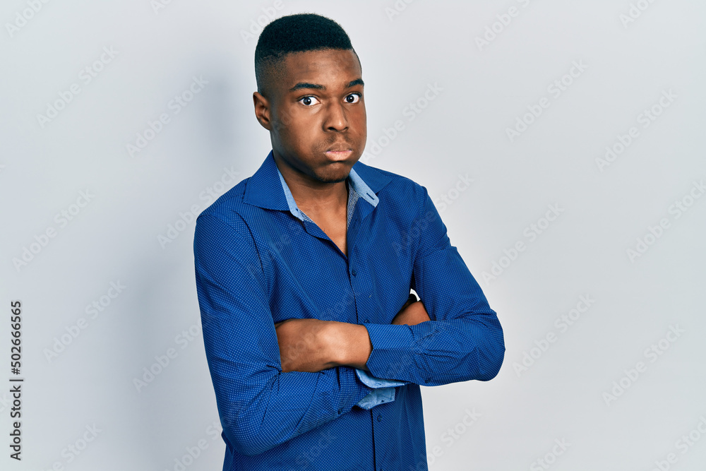 Young african american man with arms crossed gesture puffing cheeks with funny face. mouth inflated with air, catching air. Young african american man with arms crossed gesture puffing cheeks with funny face. mouth inflated with air, catching air.
