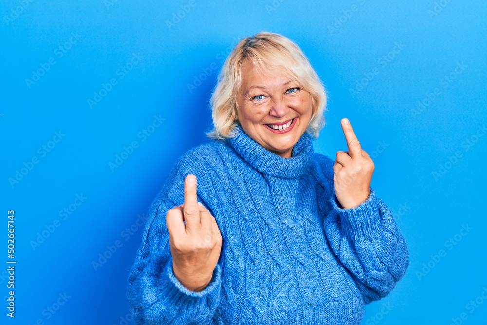 Middle age blonde woman wearing casual clothes showing middle finger doing fuck you bad expression, provocation and rude attitude. screaming excited Middle age blonde woman wearing casual clothes showing middle finger doing fuck you bad expression, provocation and rude attitude. screaming excited