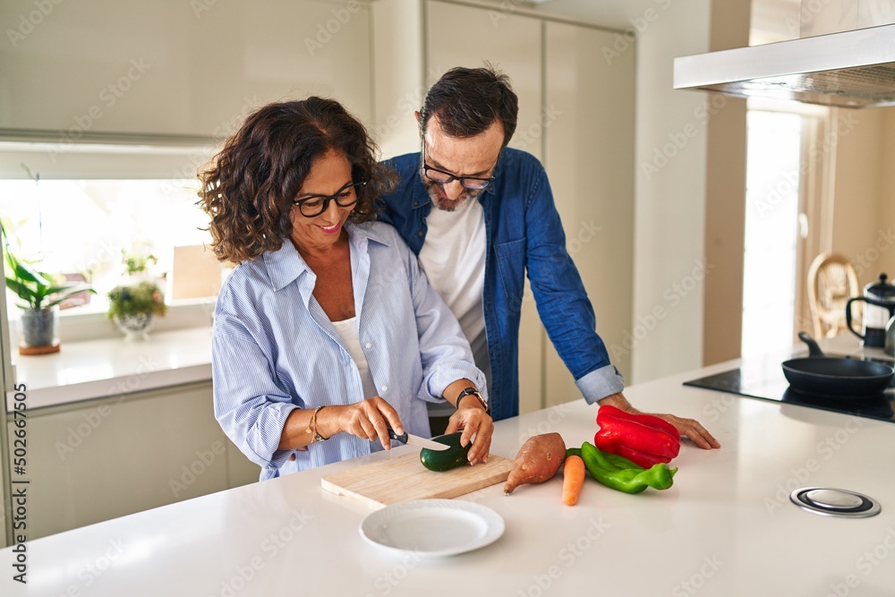 Middle age hispanic couple hugging each other cooking at kitchen Middle age hispanic couple hugging each other cooking at kitchen