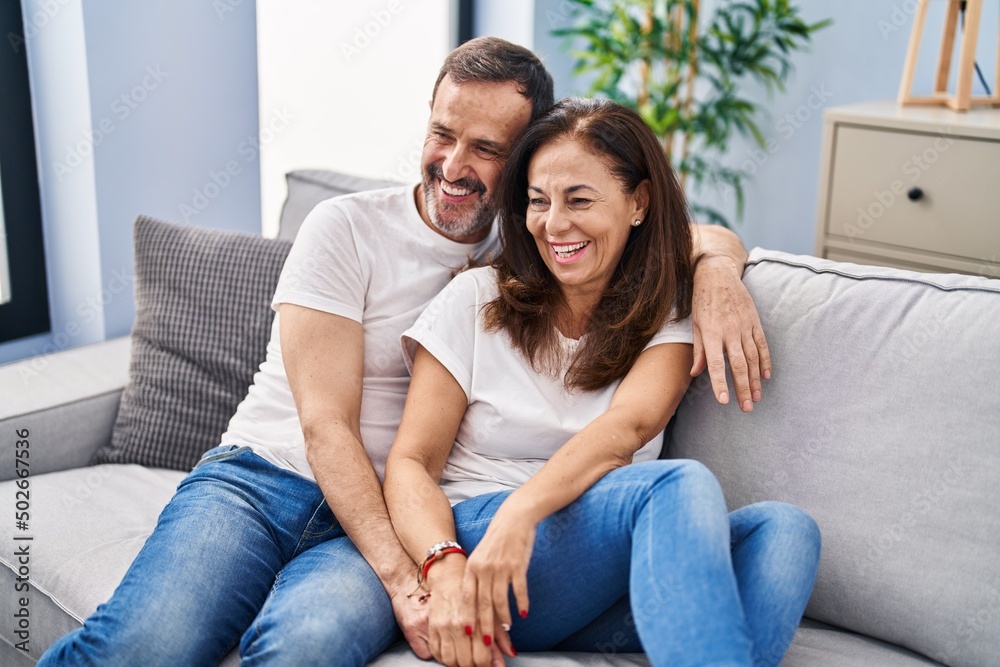 Middle age man and woman couple hugging each other sitting on sofa at home Middle age man and woman couple hugging each other sitting on sofa at home
