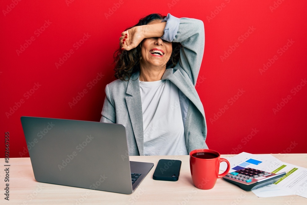 Beautiful middle age woman working at the office drinking a cup of coffee smiling cheerful playing peek a boo with hands showing face. surprised and exited Beautiful middle age woman working at the office drinking a cup of coffee smiling cheerful playing peek a boo with hands showing face. surprised and exited