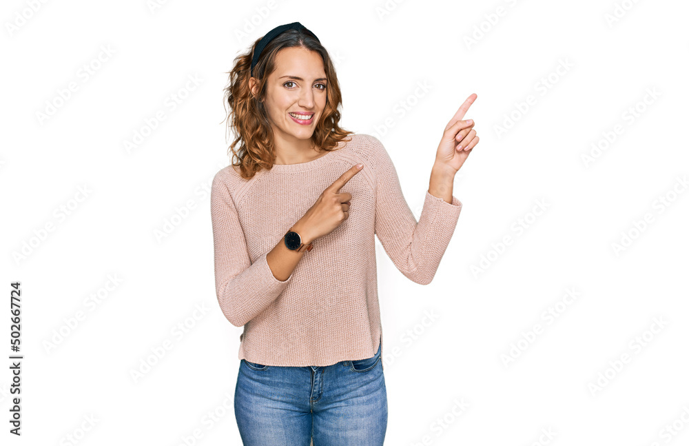 Beautiful young caucasian woman wearing casual sweater smiling and looking at the camera pointing with two hands and fingers to the side. Beautiful young caucasian woman wearing casual sweater smiling and looking at the camera pointing with two hands and fingers to the side.