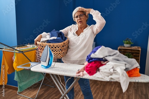 Middle age woman stressed doing chores at laundry room