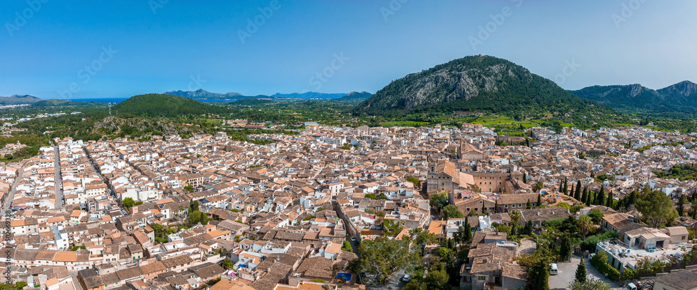 Naklejka premium Aerial view of Pollenca, Mallorca, Spain. Small town with a view into a green and rocky landscape.