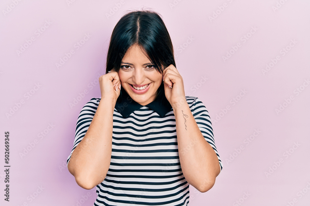 Young hispanic woman wearing casual clothes covering ears with fingers with annoyed expression for the noise of loud music. deaf concept. Young hispanic woman wearing casual clothes covering ears with fingers with annoyed expression for the noise of loud music. deaf concept.