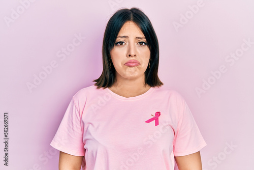 Young hispanic woman wearing pink cancer ribbon on t shirt depressed and worry for distress, crying angry and afraid. sad expression.