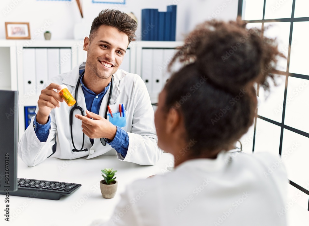 Man and woman wearing doctor uniform having medical consultation prescribe pills at clinic Man and woman wearing doctor uniform having medical consultation prescribe pills at clinic
