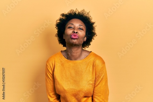 Young african american woman wearing casual clothes looking at the camera blowing a kiss on air being lovely and sexy. love expression. © Krakenimages.com