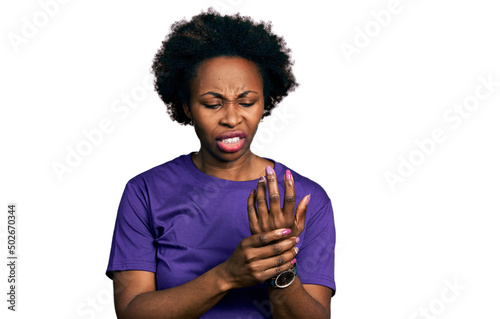 African american woman with afro hair wearing casual purple t shirt suffering pain on hands and fingers, arthritis inflammation