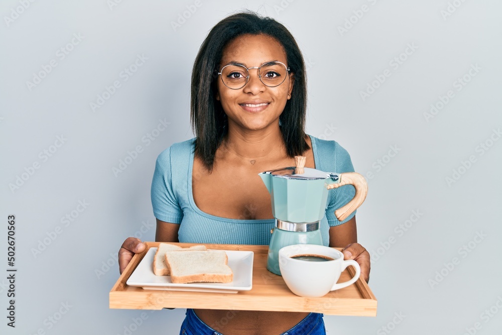 Young african american girl holding tray with breakfast food smiling with a happy and cool smile on face. showing teeth. Young african american girl holding tray with breakfast food smiling with a happy and cool smile on face. showing teeth.