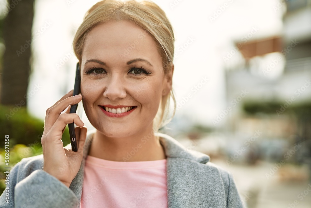 Young blonde businesswoman smiling happy talking on the smartphone at the city. Young blonde businesswoman smiling happy talking on the smartphone at the city.