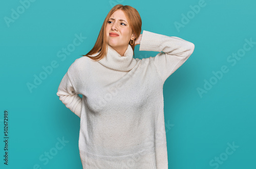 Young irish woman wearing casual winter sweater suffering of neck ache injury, touching neck with hand, muscular pain © Krakenimages.com