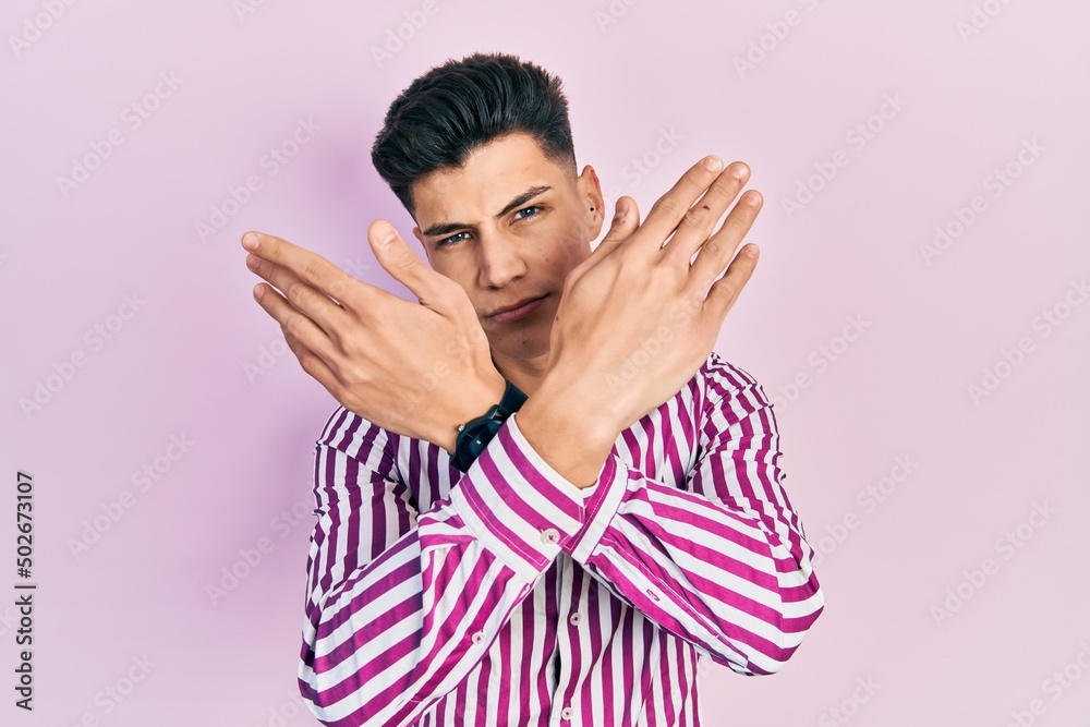 Young hispanic man wearing casual clothes rejection expression crossing arms and palms doing negative sign, angry face Young hispanic man wearing casual clothes rejection expression crossing arms and palms doing negative sign, angry face