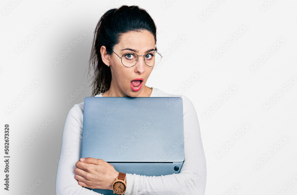 Young hispanic woman working using computer laptop in shock face, looking skeptical and sarcastic, surprised with open mouth Young hispanic woman working using computer laptop in shock face, looking skeptical and sarcastic, surprised with open mouth