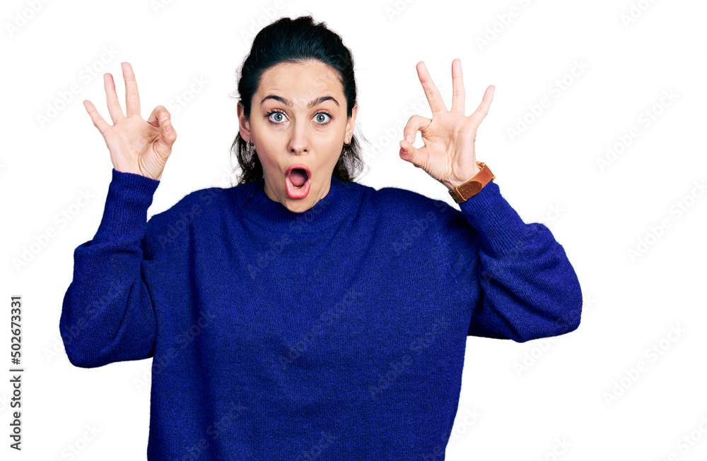 Fototapeta premium Young hispanic woman wearing casual clothes looking surprised and shocked doing ok approval symbol with fingers. crazy expression