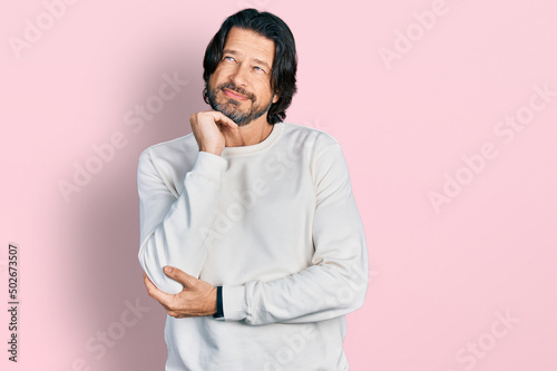 Middle age caucasian man wearing casual clothes with hand on chin thinking about question, pensive expression. smiling and thoughtful face. doubt concept.