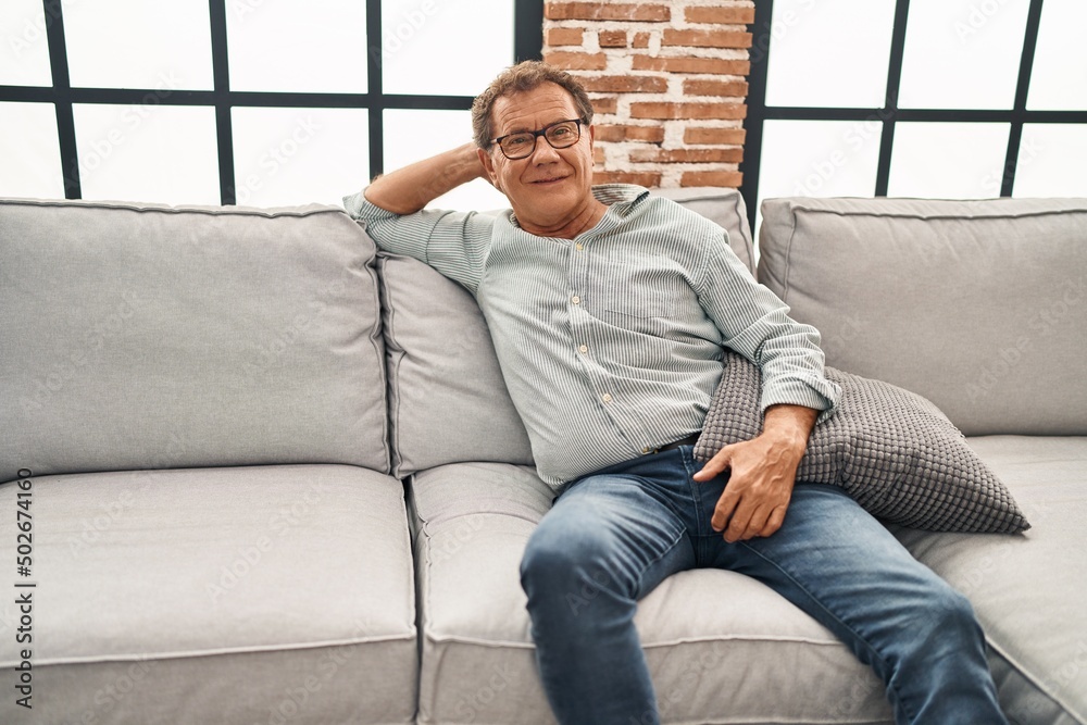 Middle age man smiling confident sitting on sofa at home