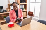 African american woman business worker using laptop writing on notebook at office