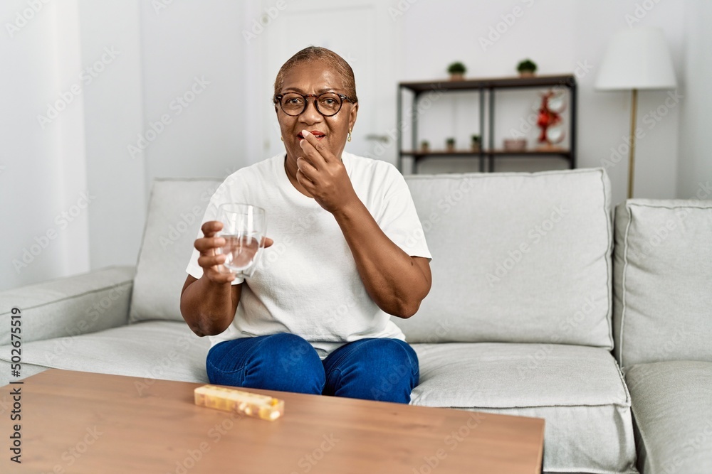 Senior african american woman smiling confident taking pills at home Senior african american woman smiling confident taking pills at home