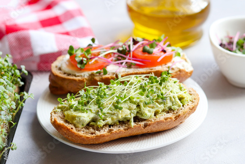 Homemade bruschetta with avocado, tomatoes and microgreens close-up. Healthy food. Tasty appetizer, snack or breakfast. Selective focus