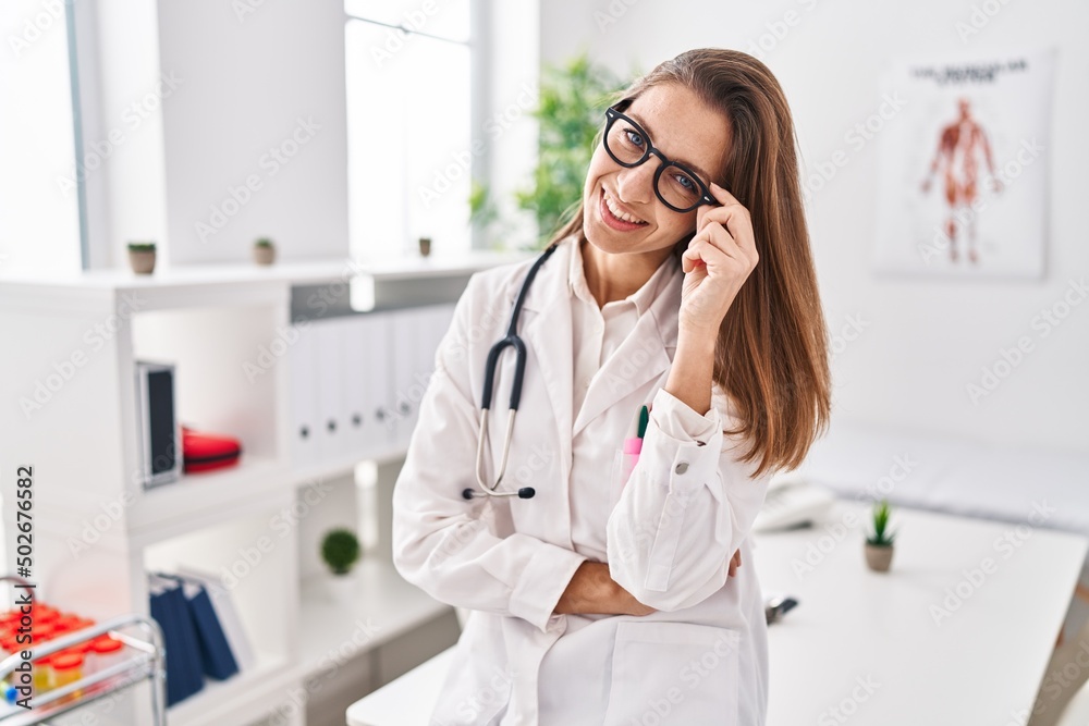Young woman wearing medical uniform standing with arms crossed gesture at clinic