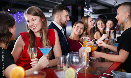 Portrait of happy young woman with colleagues enjoying corporate party at a bar