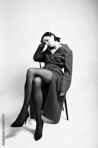 beautiful woman in a coat sits on a chair