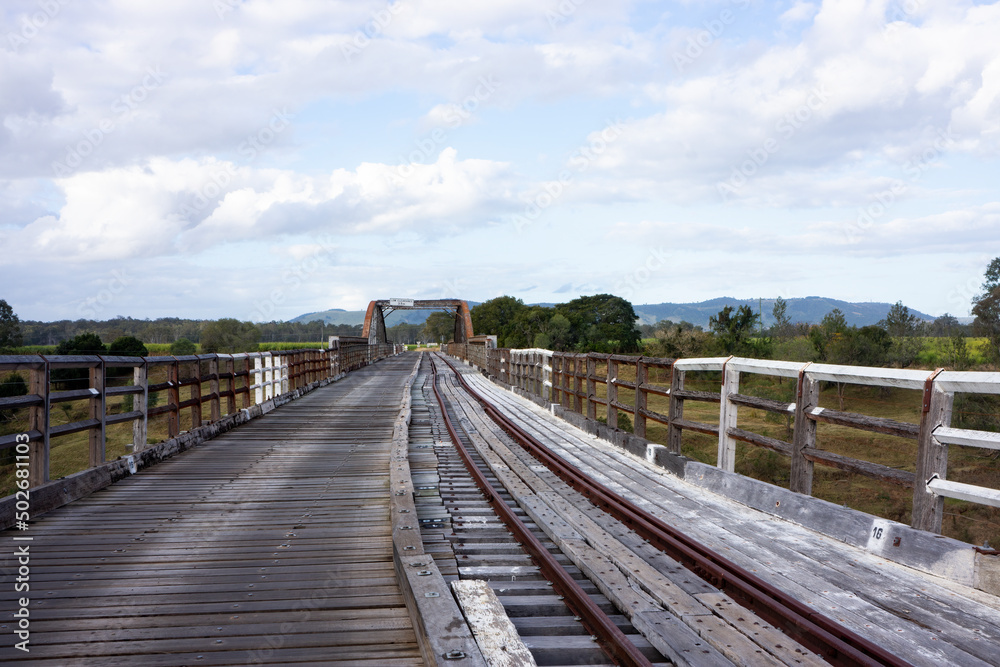 Wonky deck with cane train rail lines on the old wooden bridge  crossing Munna Creek at Miva in the South Burnett region of Queensland Australia.