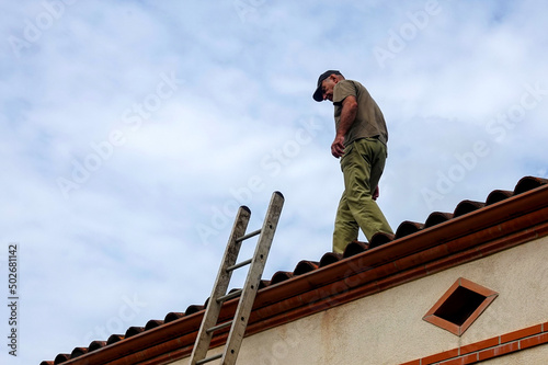 The man at the edge of the roof descend by ledder.