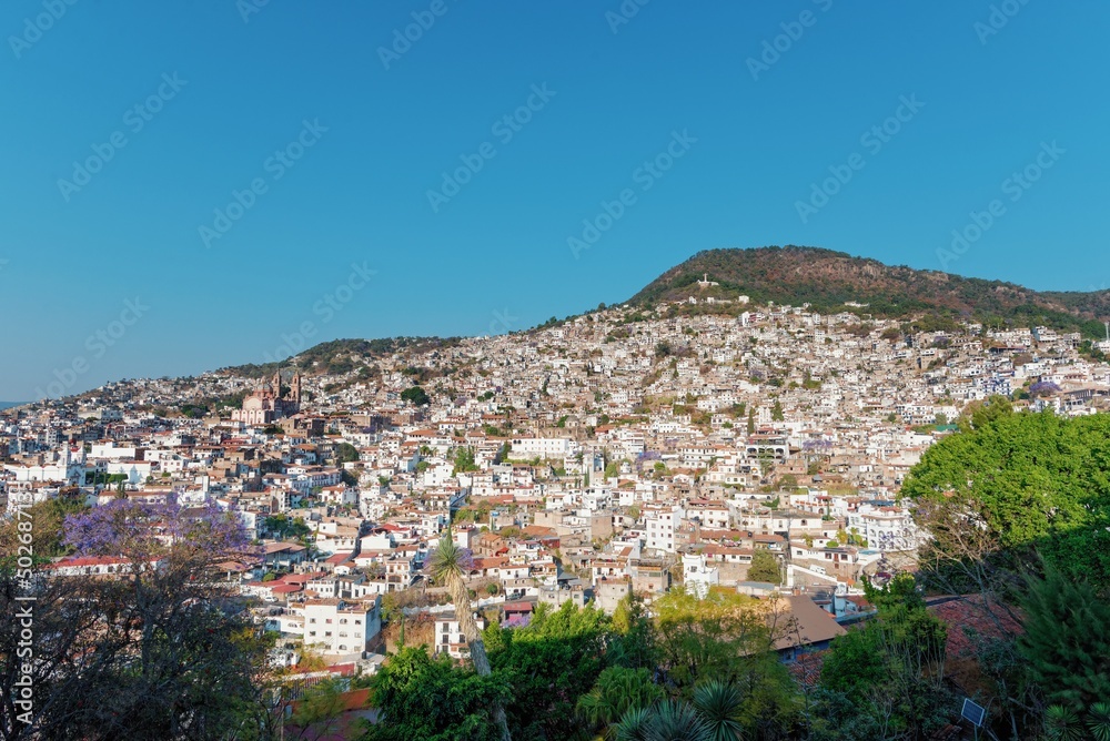 Colonial city on a mountainside before sunset. The architecture is illuminated by the rays of the sun. Evening sky. The cramped streets of Taxco in Mexico