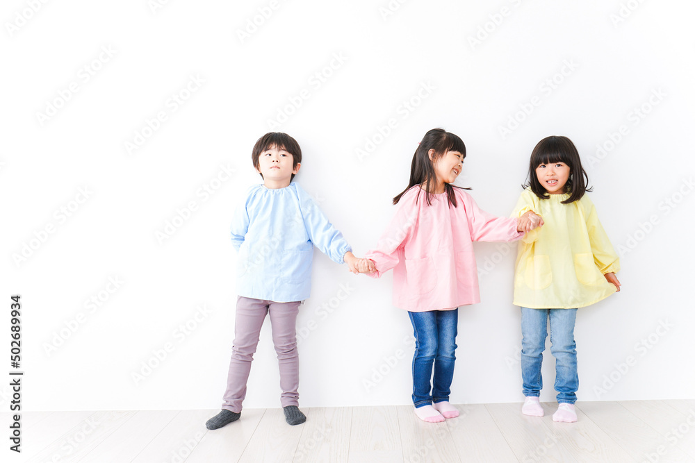 Three kindergarteners lined up on the wall