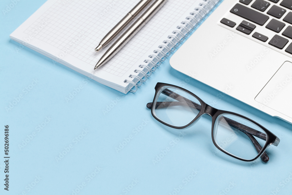 Fototapeta premium Office desk with supplies, glasses and laptop