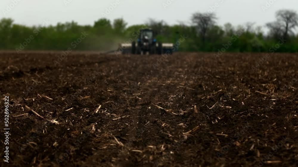 A modern tractor with sows a field. . A farmer on a tractor plows dusty arid soil and sows cereal grains. Agribusiness in the spring. Agricultural work in the fields, agribusiness. Selective focusing A modern tractor with sows a field. . A farmer on a tractor plows dusty arid soil and sows cereal grains. Agribusiness in the spring. Agricultural work in the fields, agribusiness. Selective focusing