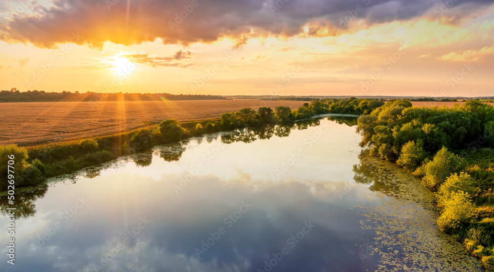 Amazing view at scenic landscape on a beautiful river and colorful sunset with reflection on water surface and glow on a background, spring season landscape