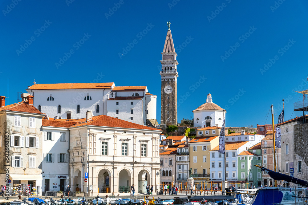 Beautiful city of Piran with Tartini Square, Monument of Giuseppe Tartini and St. George Church on a warm, sunny eastertime day against deep blue sky. Popular tourist attraction of Slovenia 