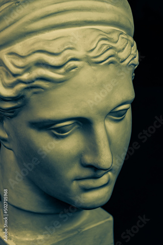 Plaster sculpture of woman face. Bronze color gypsum copy of ancient statue of Diana head for artists on black background. Diana in Roman mythology the goddess of nature and hunting. Renaissance epoch