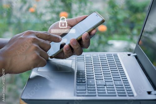 Asian businessman using the smart mobile phone to access on phone with laptop for validate password for biometric two steps authentication to unlock security, Business Technology security Concept photo