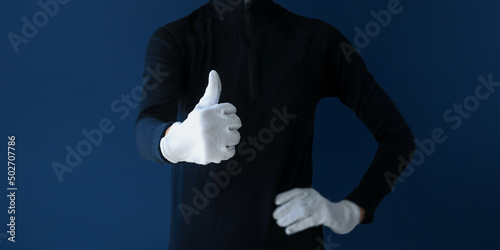 Two male hands with thumbs up with white gloves on black background. magician hand wearing white glove showing Thumbs up signal isolated on clean dark background.