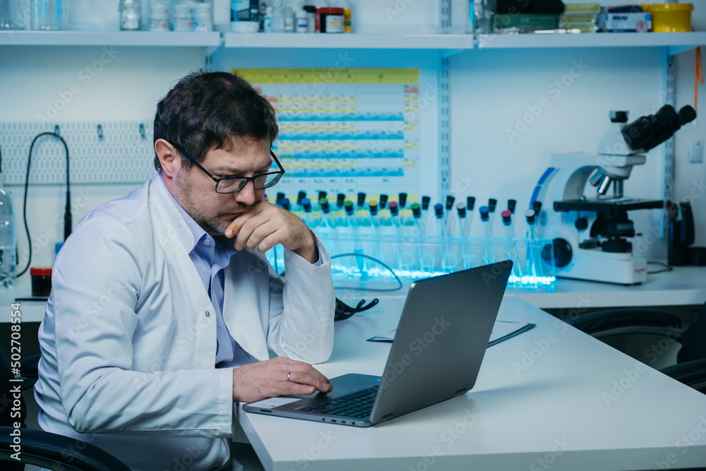 Male scientist working in the laboratory with laptop computer and liquid chemical