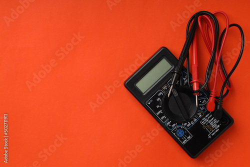 Multimeter on orange background, space for text